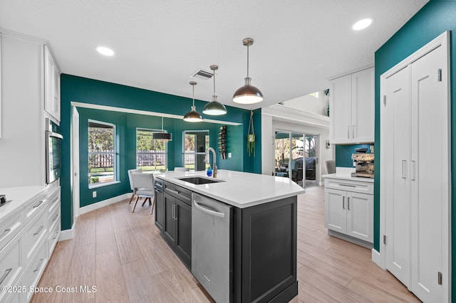 kitchen featuring a sink, light wood-style floors, white cabinets, light countertops, and appliances with stainless steel finishes