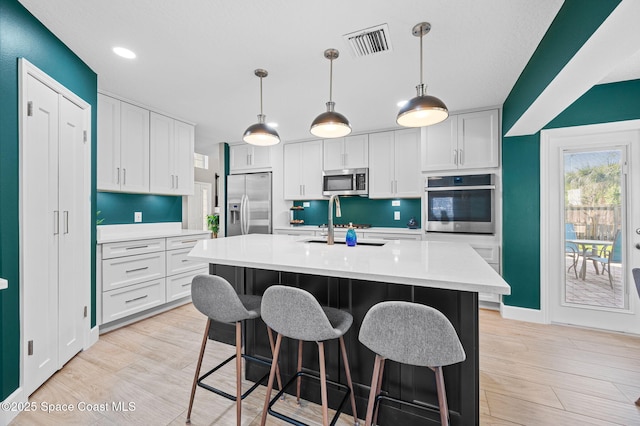 kitchen with appliances with stainless steel finishes, light countertops, light wood-type flooring, and visible vents