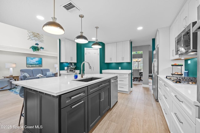 kitchen featuring stainless steel appliances, a sink, visible vents, and white cabinets