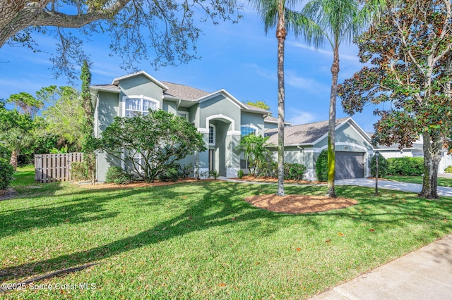 view of front of house featuring an attached garage, fence, driveway, stucco siding, and a front yard