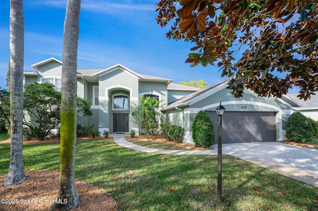 view of front of home with a front yard, driveway, an attached garage, and stucco siding