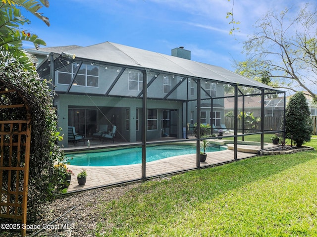 rear view of house featuring an outdoor pool, a lawn, a patio, a chimney, and stucco siding