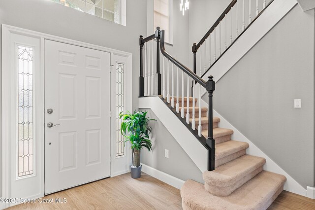 foyer entrance with stairs, a high ceiling, baseboards, and wood finished floors