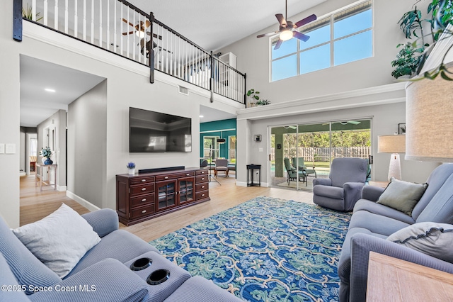 living room featuring a ceiling fan, visible vents, baseboards, and wood finished floors