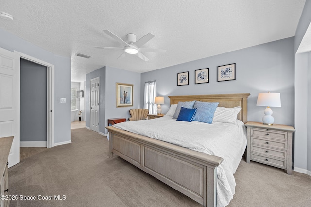 bedroom with baseboards, visible vents, a textured ceiling, and light colored carpet