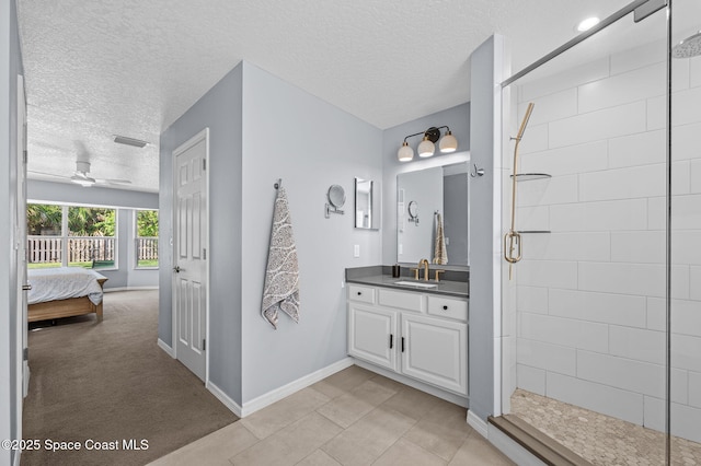 ensuite bathroom featuring a stall shower, baseboards, ceiling fan, a textured ceiling, and vanity