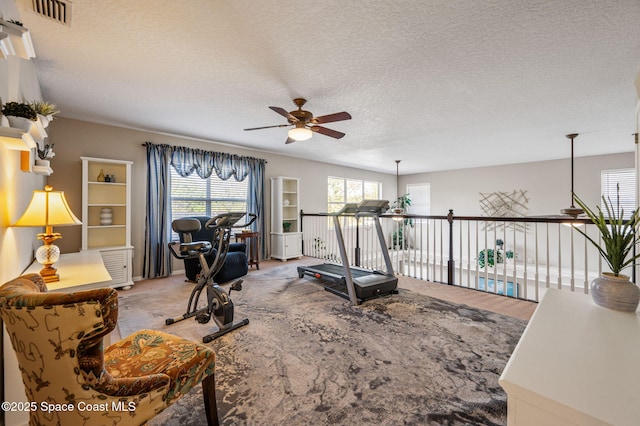 workout room featuring ceiling fan, a textured ceiling, carpet, and visible vents