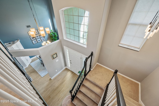 entrance foyer with baseboards, visible vents, wood finished floors, stairs, and a notable chandelier