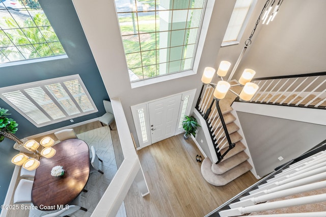 entryway with a notable chandelier, plenty of natural light, stairs, and wood finished floors