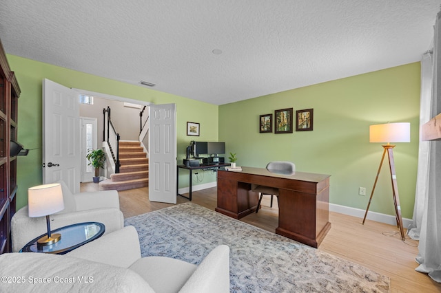 office area featuring visible vents, a textured ceiling, baseboards, and wood finished floors