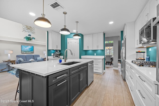 kitchen with white cabinets, visible vents, stainless steel appliances, and a sink