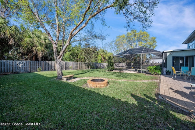 view of yard featuring a fire pit, a patio area, a fenced backyard, and a lanai