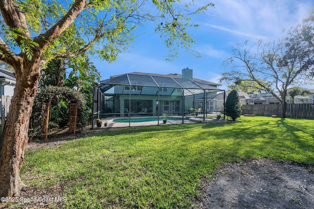 back of property featuring a fenced in pool, glass enclosure, a chimney, fence, and a yard