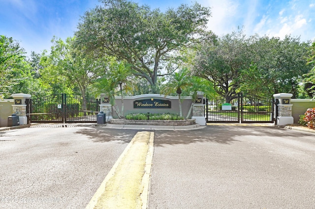 view of road featuring a gate, a gated entry, and curbs