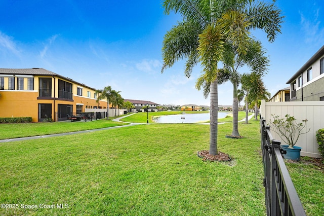 view of yard featuring a residential view, a water view, and fence