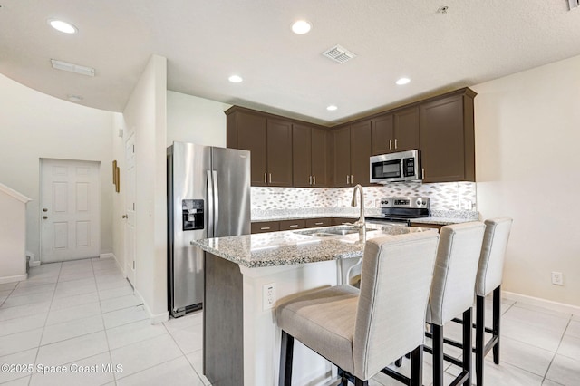 kitchen featuring appliances with stainless steel finishes, visible vents, a sink, and dark brown cabinetry