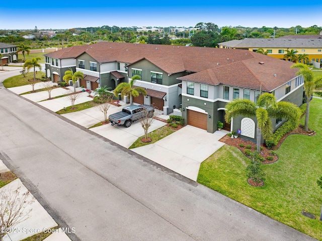 view of front of property with driveway, an attached garage, a residential view, and stucco siding