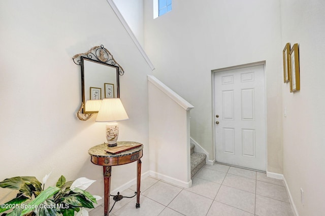 interior space with stairs, a high ceiling, light tile patterned flooring, and baseboards