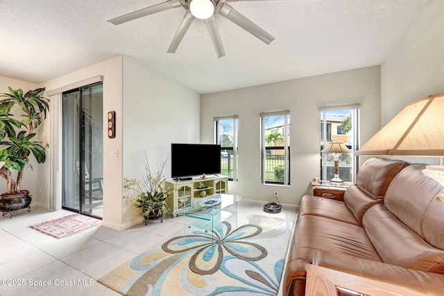 living room with a textured ceiling, a ceiling fan, a wealth of natural light, and light tile patterned flooring