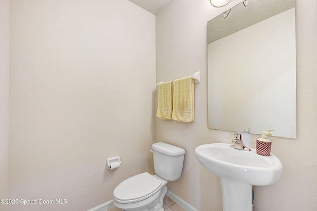 half bath featuring toilet, baseboards, and tile patterned floors