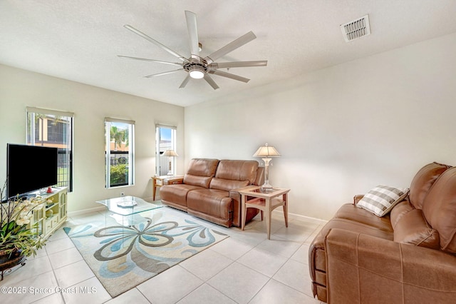 living area featuring light tile patterned floors, a textured ceiling, visible vents, and a ceiling fan