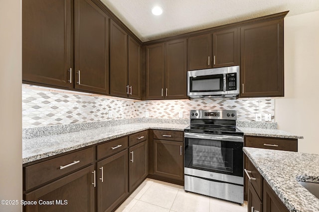 kitchen featuring dark brown cabinetry, appliances with stainless steel finishes, and light stone counters