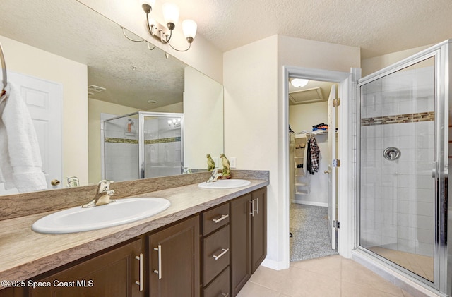 bathroom with tile patterned flooring, a sink, a shower stall, and double vanity