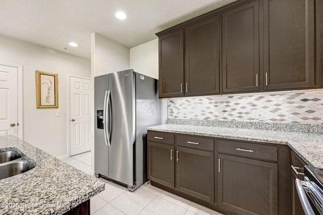 kitchen featuring light tile patterned floors, recessed lighting, dark brown cabinets, appliances with stainless steel finishes, and backsplash