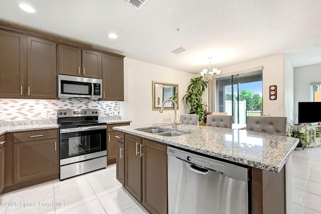 kitchen with tasteful backsplash, visible vents, an island with sink, stainless steel appliances, and a sink