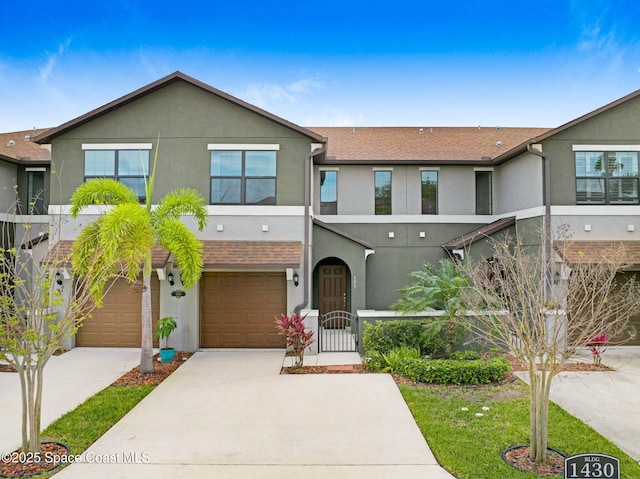 townhome / multi-family property with driveway, a garage, a gate, fence, and stucco siding