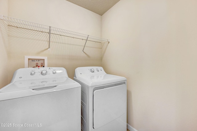 washroom featuring a textured ceiling, laundry area, and washing machine and dryer