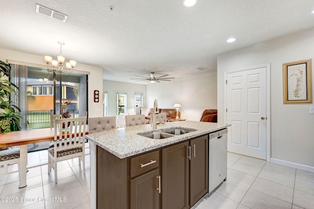 kitchen with light tile patterned floors, a sink, visible vents, stainless steel dishwasher, and an island with sink