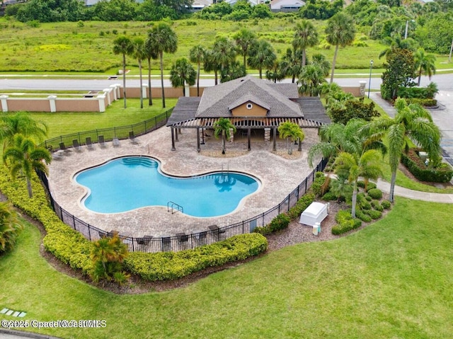 community pool with a yard, a patio area, and fence