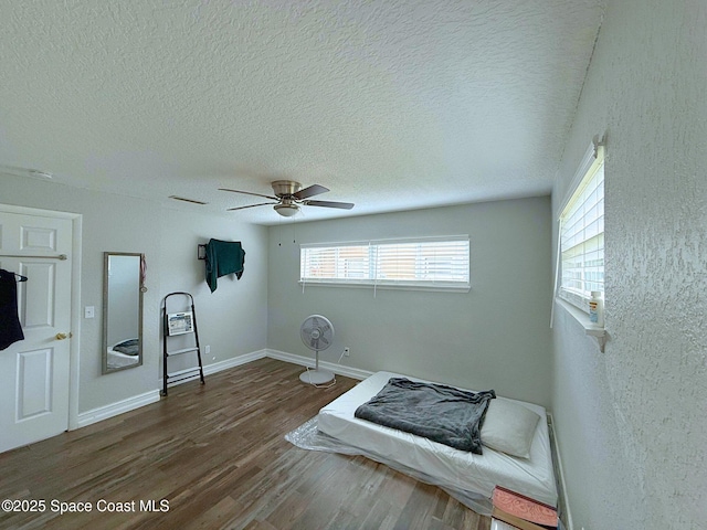 bedroom featuring baseboards, visible vents, ceiling fan, wood finished floors, and a textured ceiling