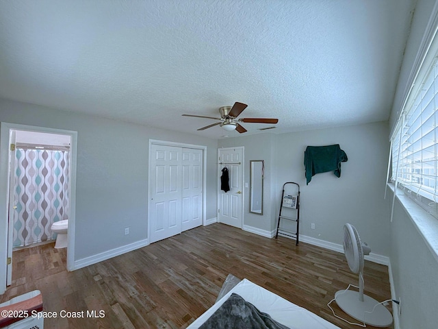 unfurnished bedroom featuring a textured ceiling, a closet, wood finished floors, and baseboards