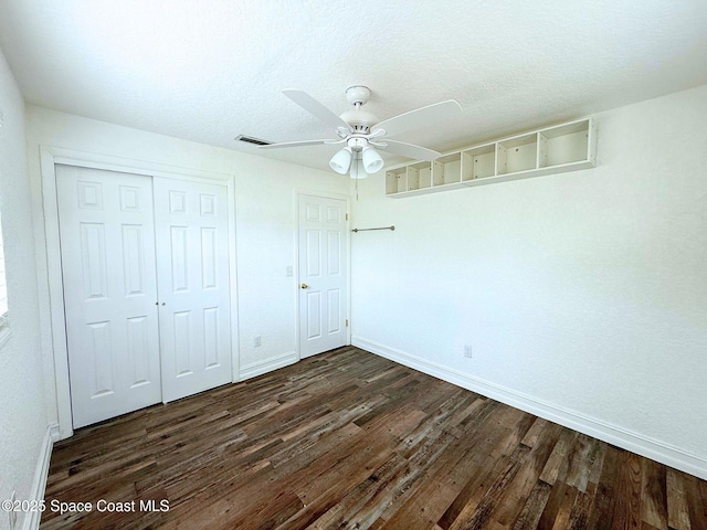 unfurnished bedroom with a closet, dark wood-style flooring, a textured ceiling, and baseboards