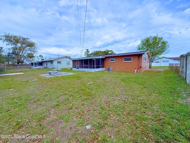 back of house featuring central air condition unit, a lawn, a sunroom, a patio area, and a fenced backyard