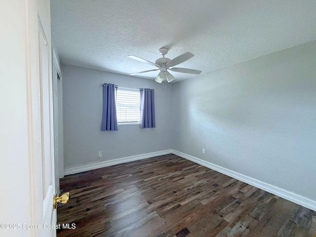 unfurnished room with dark wood-style flooring, a textured ceiling, and baseboards