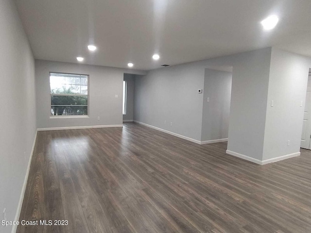 spare room featuring dark wood-type flooring, recessed lighting, and baseboards