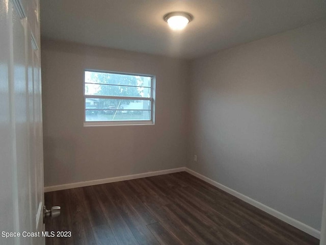 empty room featuring dark wood finished floors and baseboards