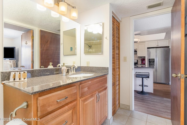 bathroom with visible vents, a textured ceiling, vanity, and tile patterned floors