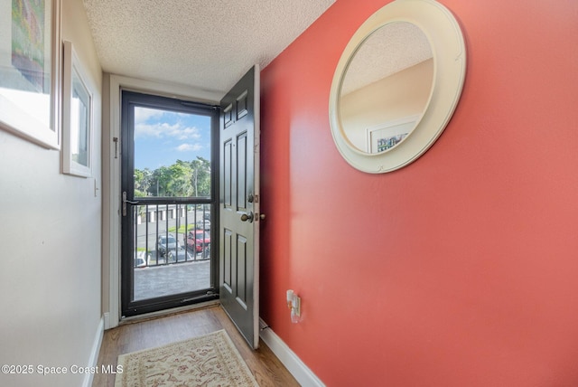 entryway with baseboards, a textured ceiling, and wood finished floors