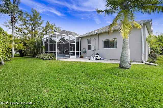 rear view of house featuring stucco siding, a yard, glass enclosure, and a patio