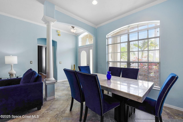 dining room featuring baseboards, crown molding, and ornate columns