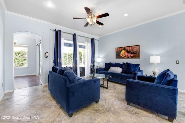 living area with baseboards, ornamental molding, arched walkways, and a wealth of natural light