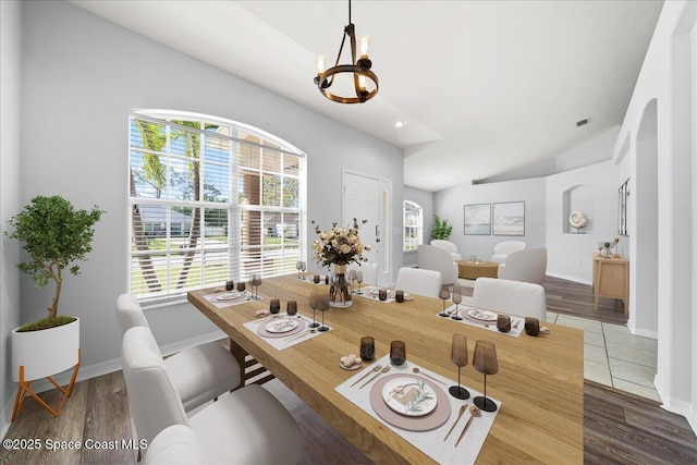 dining space with lofted ceiling, a notable chandelier, baseboards, and wood finished floors