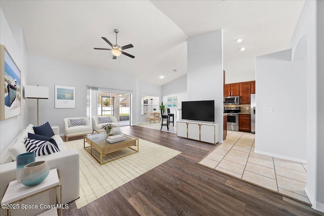 living area with recessed lighting, a ceiling fan, high vaulted ceiling, light wood-type flooring, and baseboards