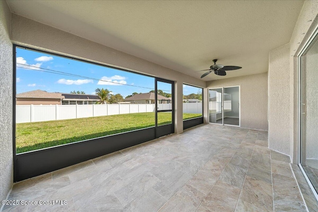 unfurnished sunroom featuring ceiling fan