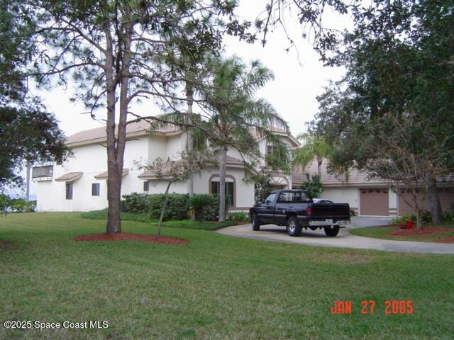 view of front of house featuring a garage, a front lawn, and stucco siding