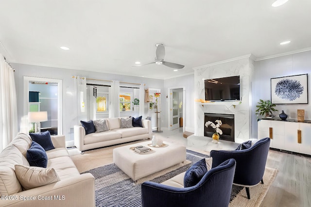 living area with recessed lighting, ornamental molding, a high end fireplace, light wood-style floors, and ceiling fan